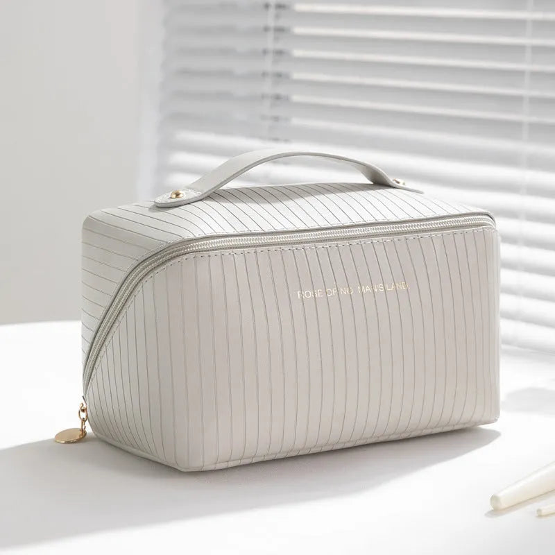 Cubic pillow-shaped PU makeup bag in a vertical pattern, shown in one of five colours: beige, black, brown, grey, or pink.