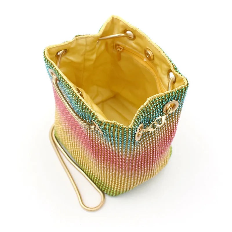 Rainbow coloured rhinestone bucket bag with a crossbody shoulder strap on a white background.