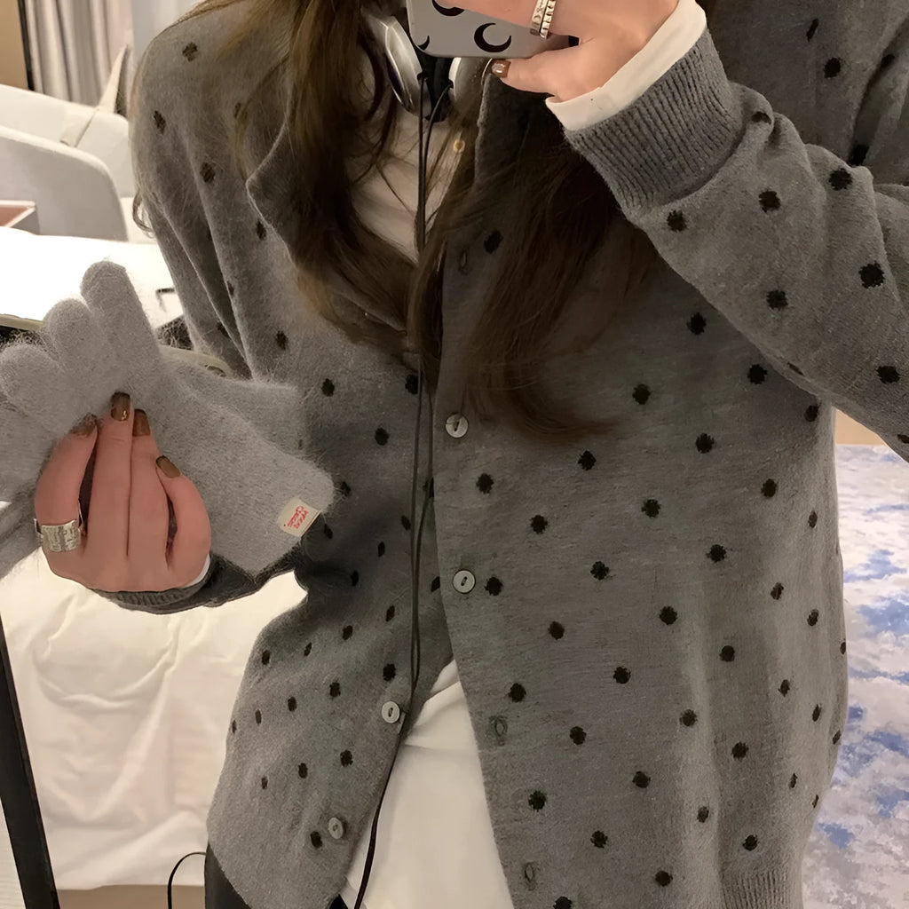 Grey dot patterned women's knitted cardigan with crochet flower detail on a hanger.