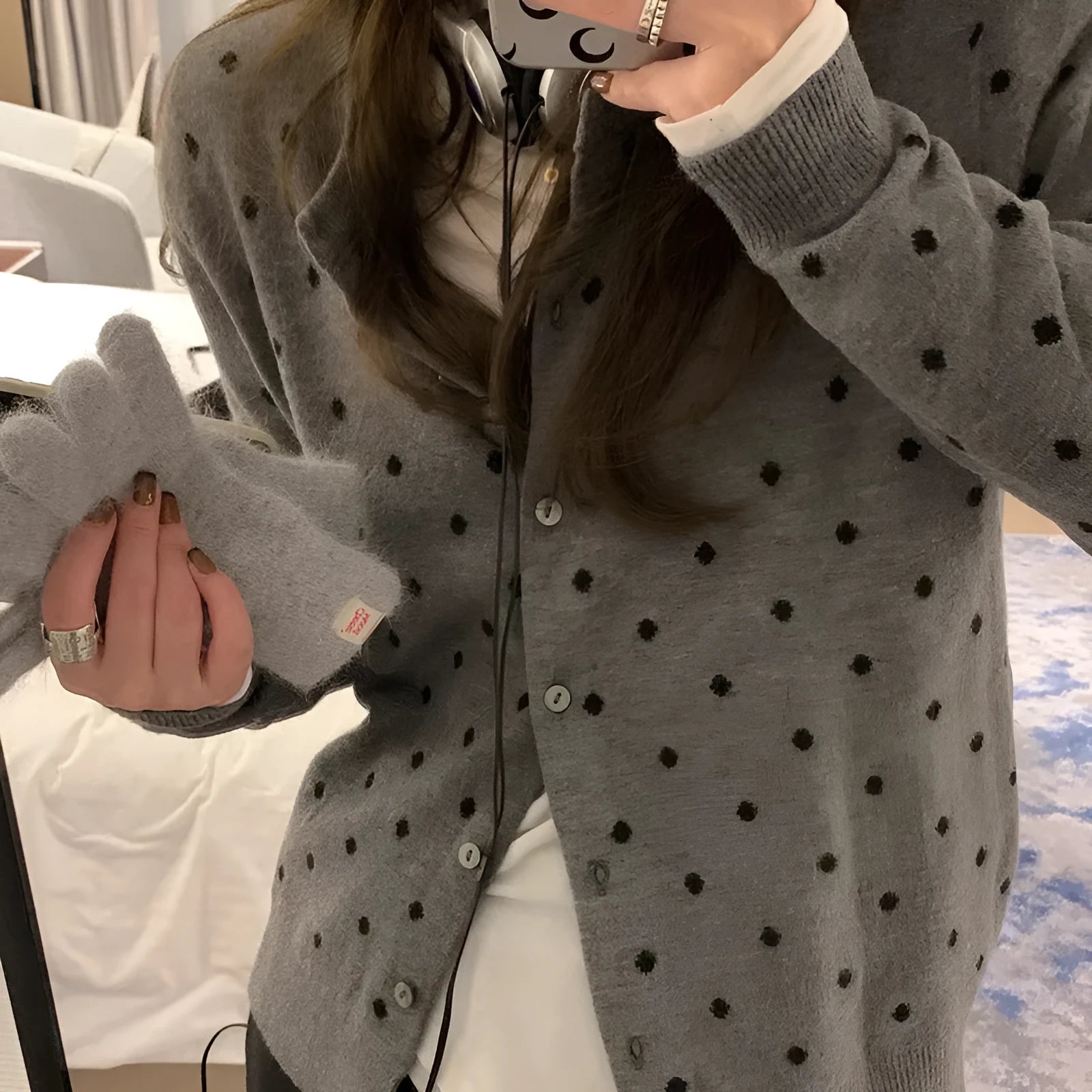 Grey dot patterned women's knitted cardigan with crochet flower detail on a hanger.