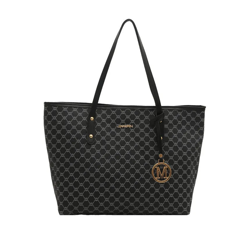 Women's black PU leather shoulder bag with sewing thread detail on a table.