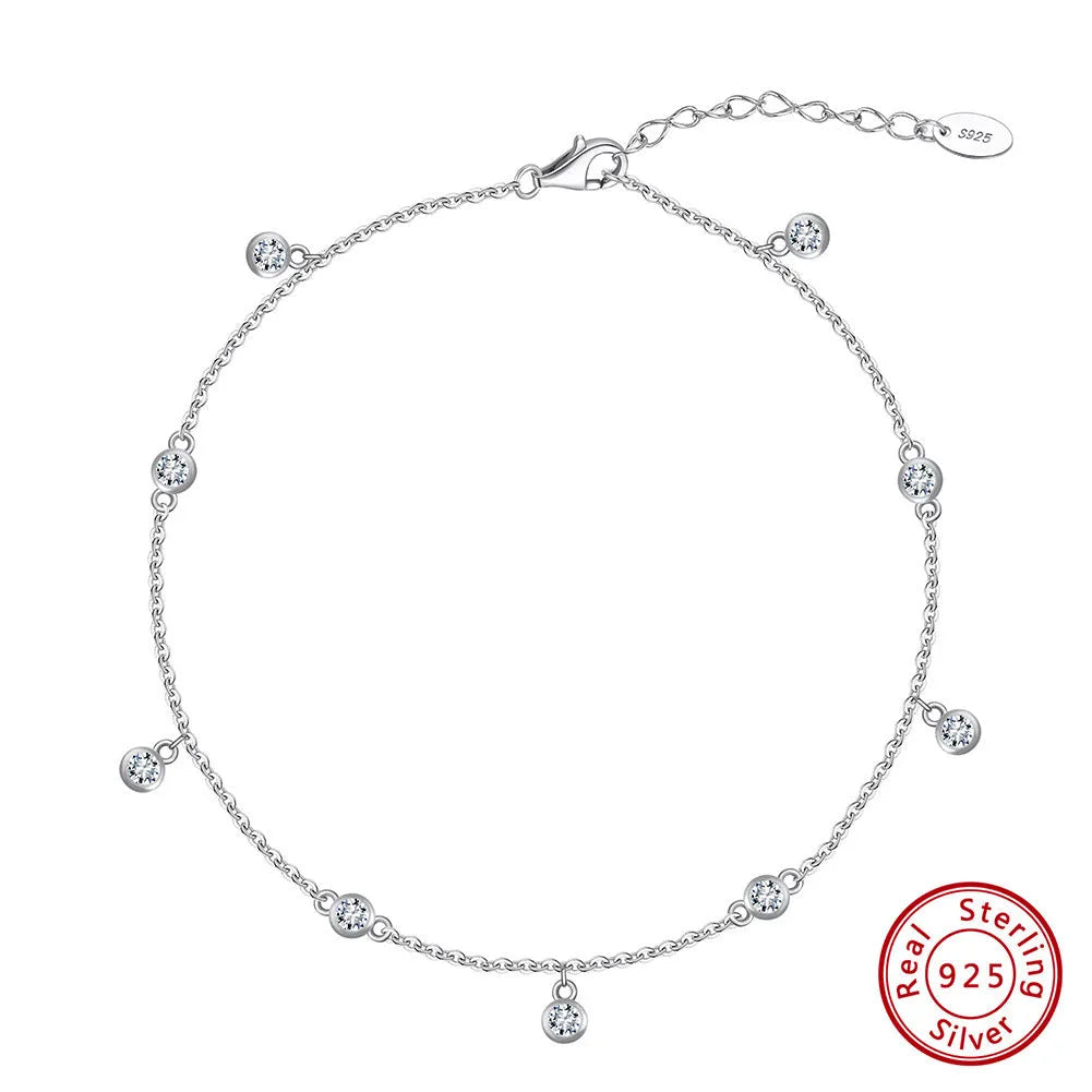 Women's silver geometric zirconium pendant anklet on an ankle, shown in gold and platinum colour options.