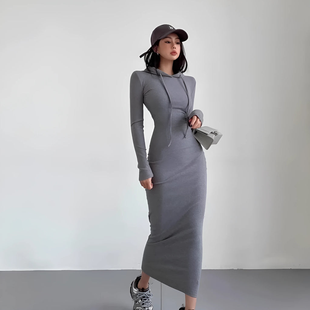 A woman wearing a light grey hooded long sleeve sheath dress with a high waist.