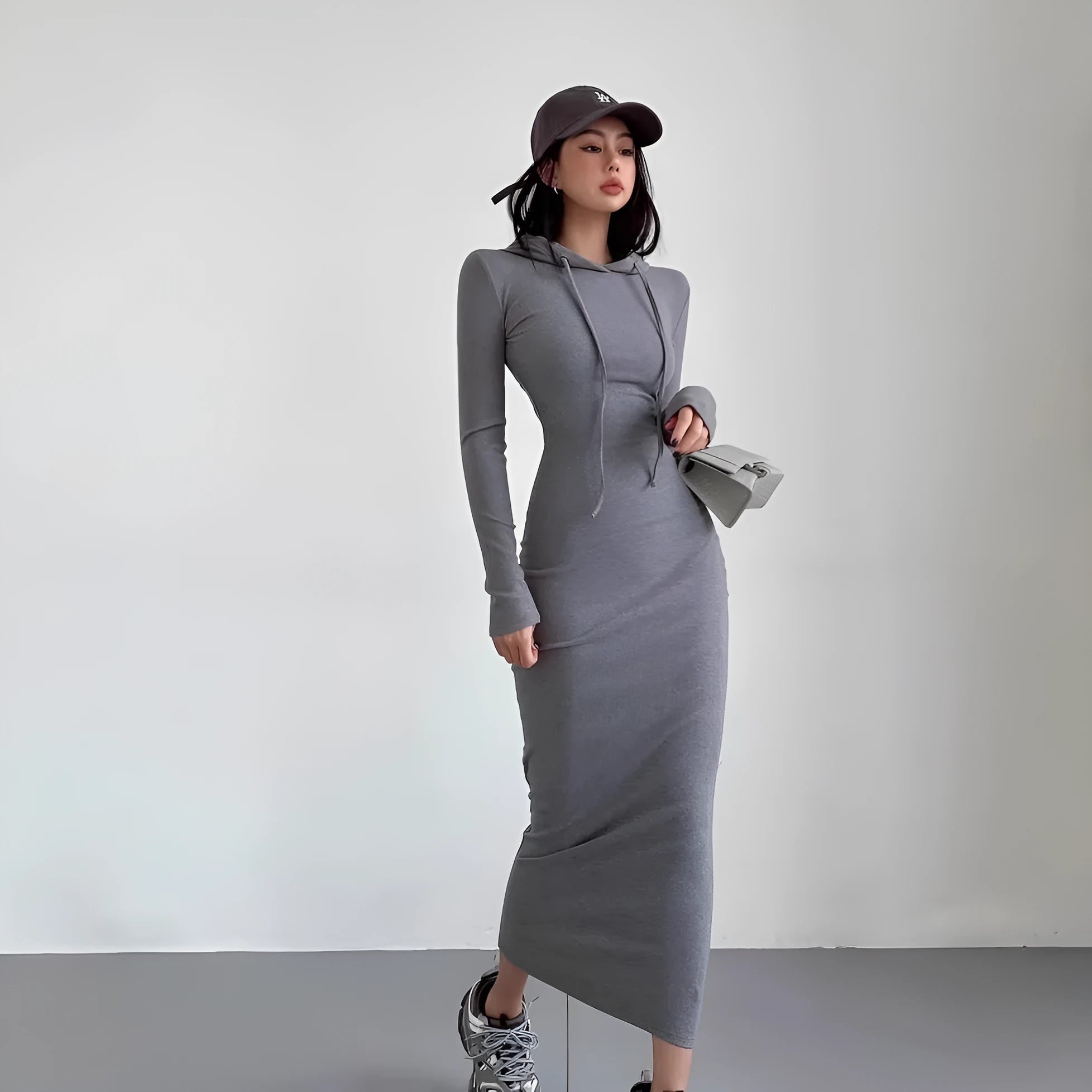 A woman wearing a light grey hooded long sleeve sheath dress with a high waist.