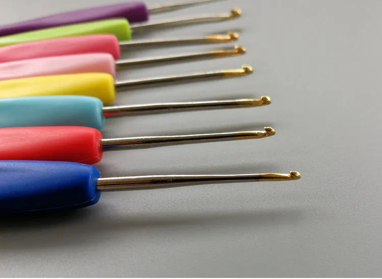Set of 16 crochet hooks in various sizes with two handle types, laid next to a grey PU storage bag.