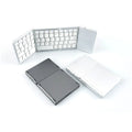 Black mini tri-fold Bluetooth keyboard unfolded next to a tablet, showing its compact size.