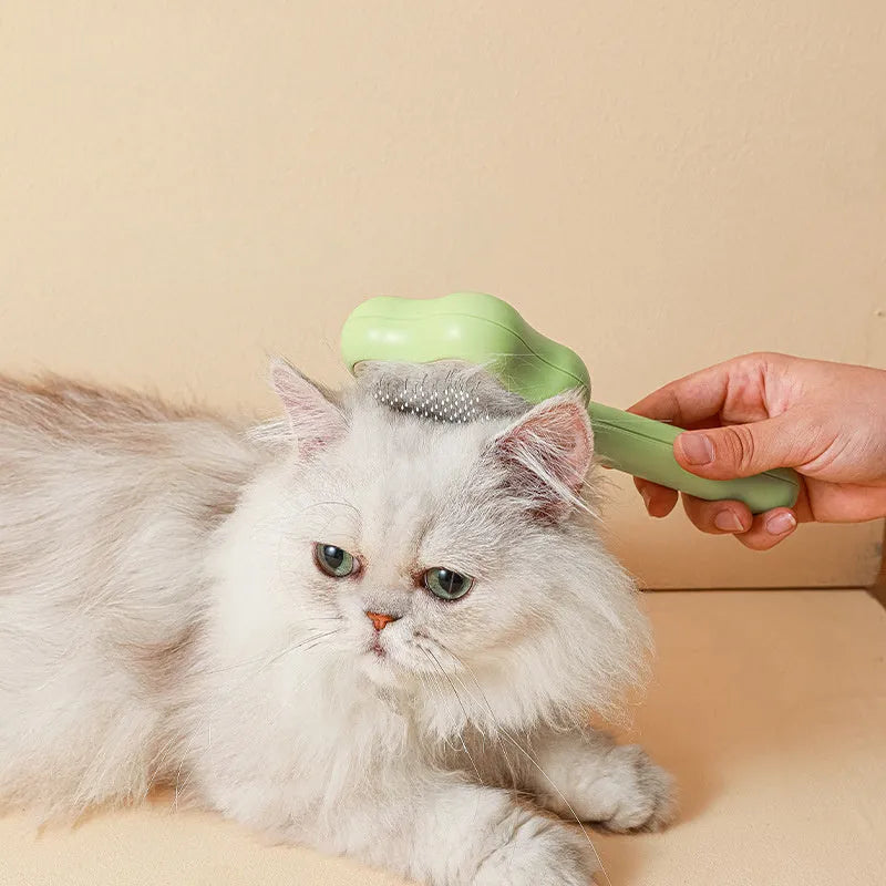 Green handle self-cleaning stainless steel needle comb for cats on a white background