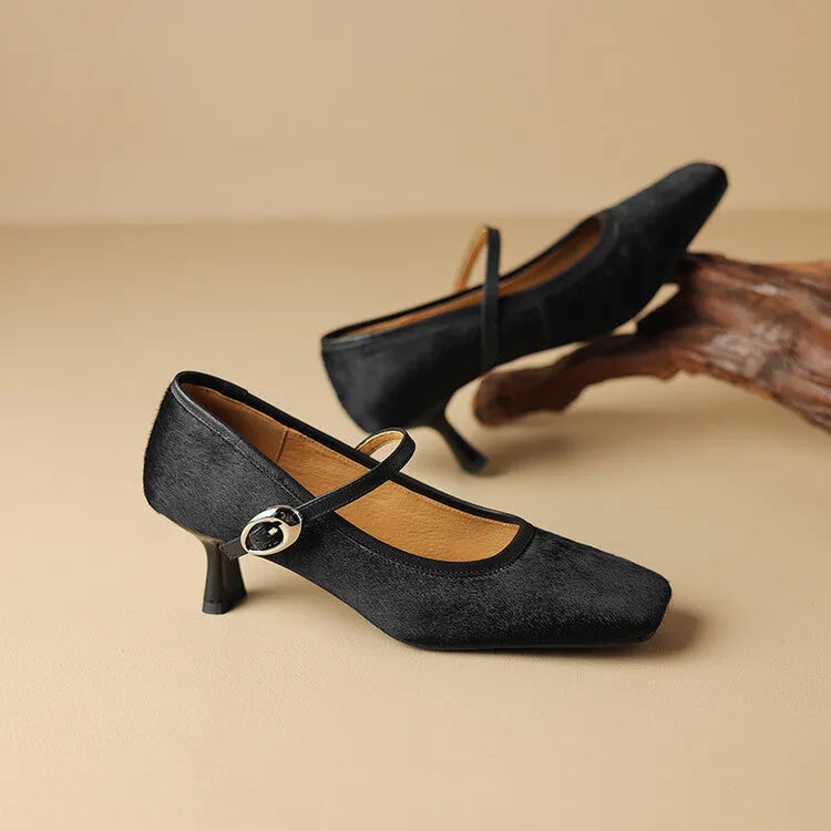 Women's black square toe stiletto heel ankle-strap shoes with horse hair upper on a neutral background.