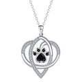 Close-up of a copper pendant necklace showing a charm with dog paw and cat footprint designs on a cross chain.