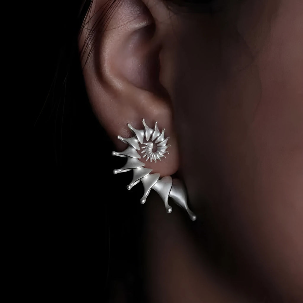 Matte finish three-dimensional conch-shaped alloy drop earrings on a plain background.