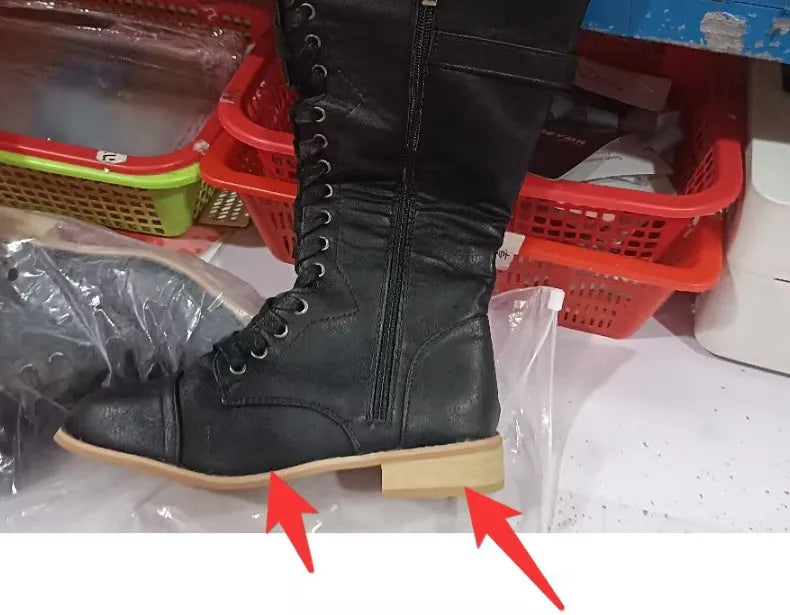 Women's black cross strap knight boots made from artificial PU, showing front strap detail.