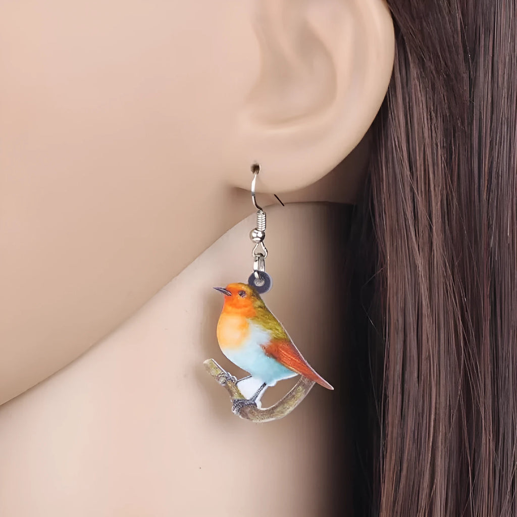 Close-up of women's acrylic earrings with a blue titmouse bird pendant and geometric snake motif design.