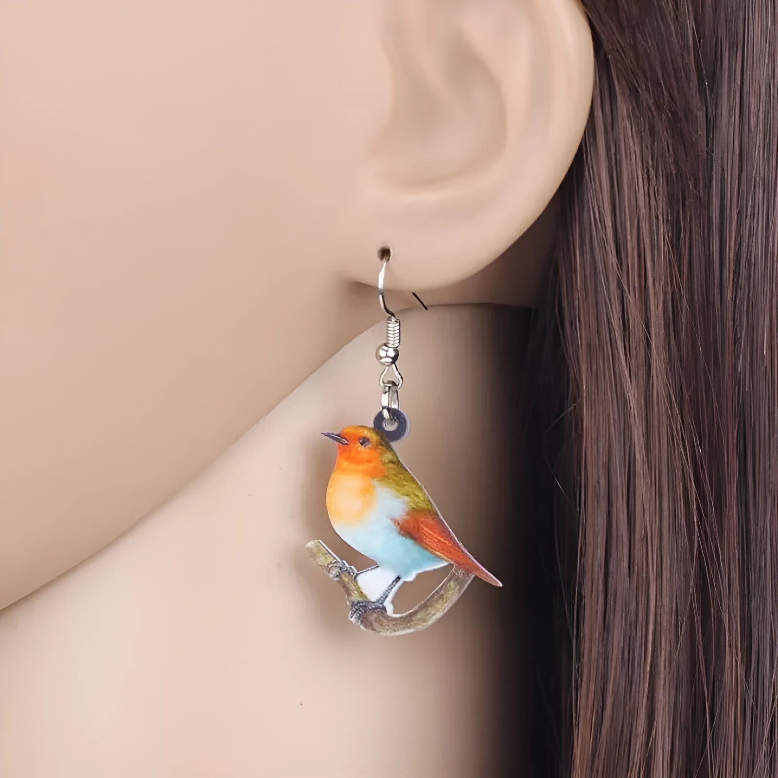 Close-up of women's acrylic earrings with a blue titmouse bird pendant and geometric snake motif design.