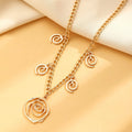 Gold tone spiral donut design necklace, bracelet, and earrings set on a white background.