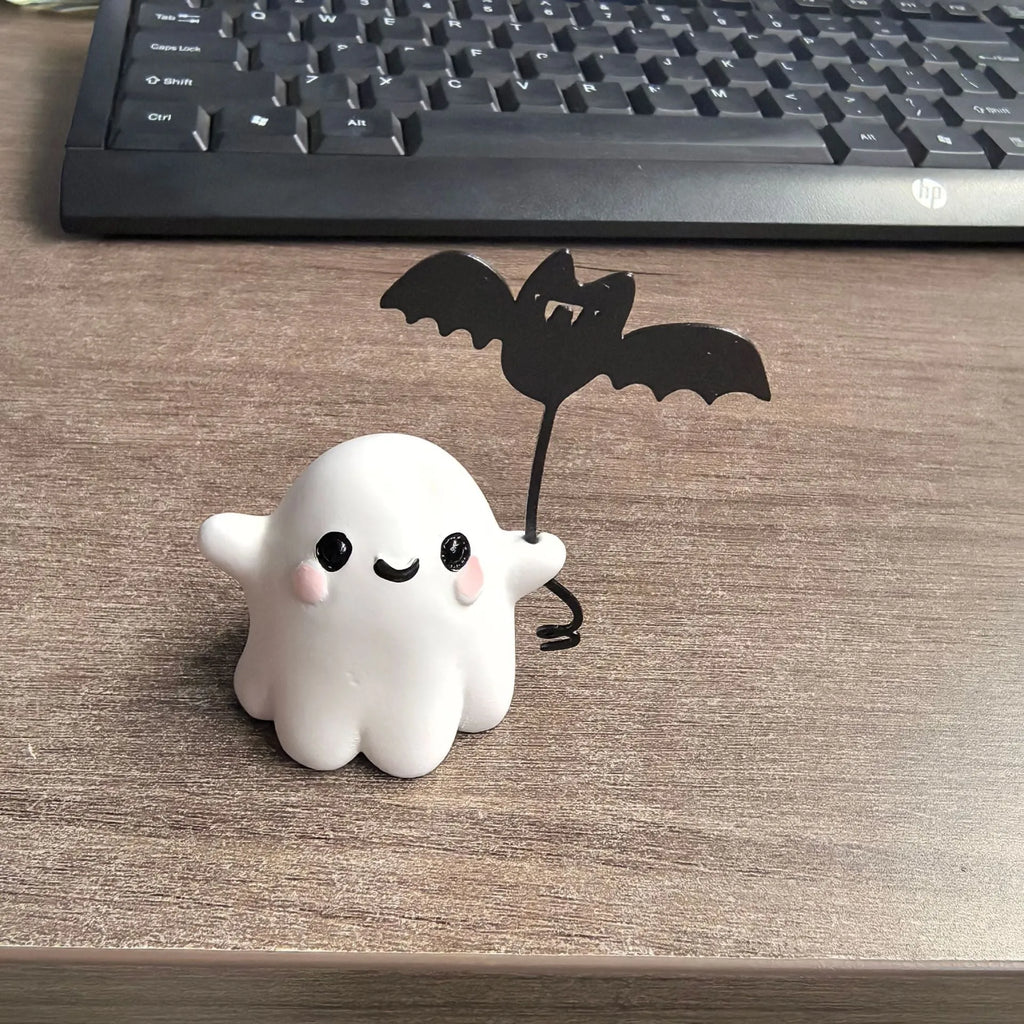Miniature resin statue of a ghost holding a bat next to a walking dog, a Halloween decoration.