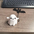 Miniature resin statue of a ghost holding a bat next to a walking dog, a Halloween decoration.