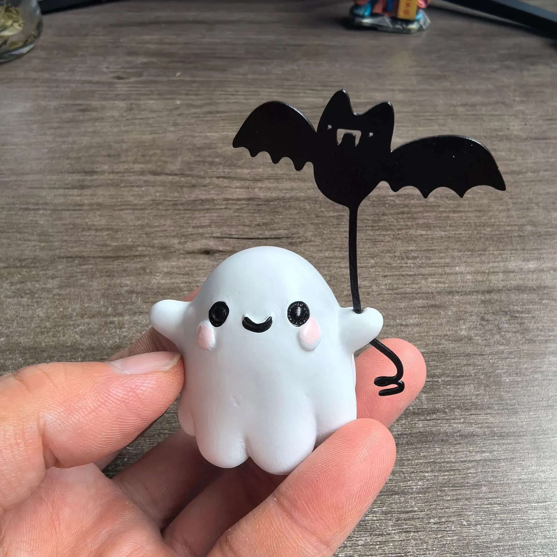 Miniature resin statue of a ghost holding a bat next to a walking dog, a Halloween decoration.