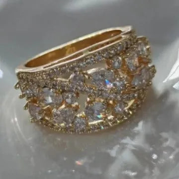 Women's hollow round fashion ring in gold tone with blue stones, showing openwork design.