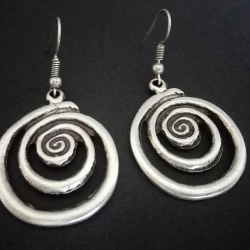 Geometric spiral alloy earrings with distressed silver finish and folk art style.