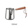 Stainless steel coffee cup with wooden handle showing interior measurement scale for latte art