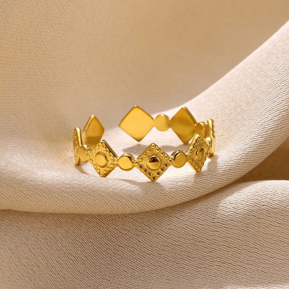 Geometric gold titanium steel ring on a neutral background.