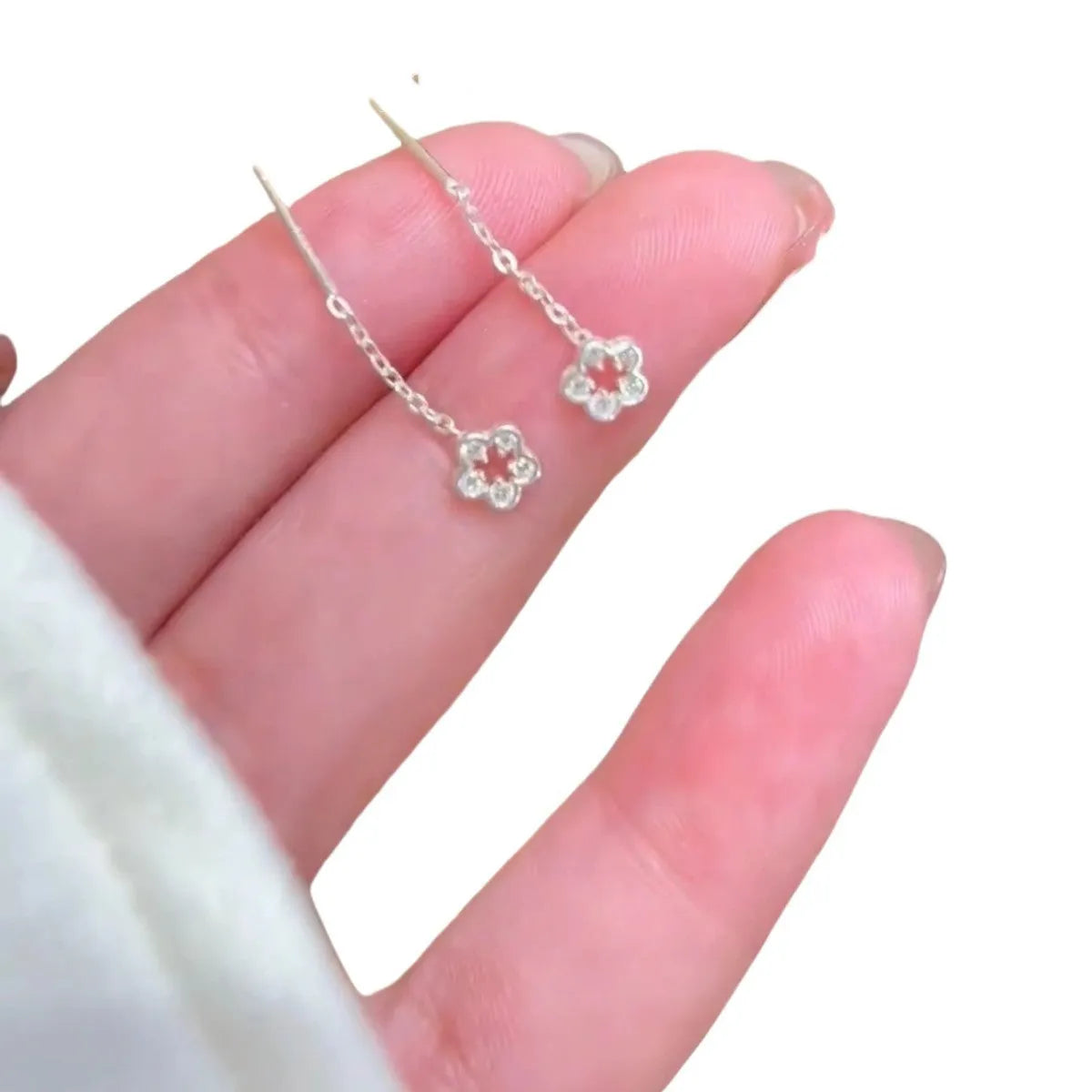 Silver hollow flower drop earrings with detailed petal design on hook closure