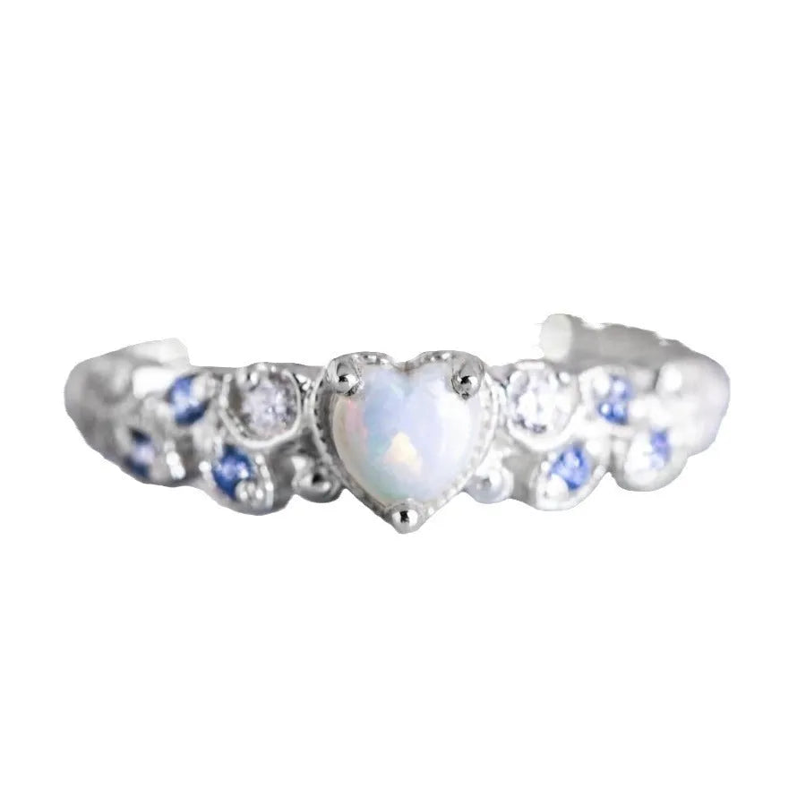 White electroplated women's ring with a peach-coloured heart shape, shown on a finger.
