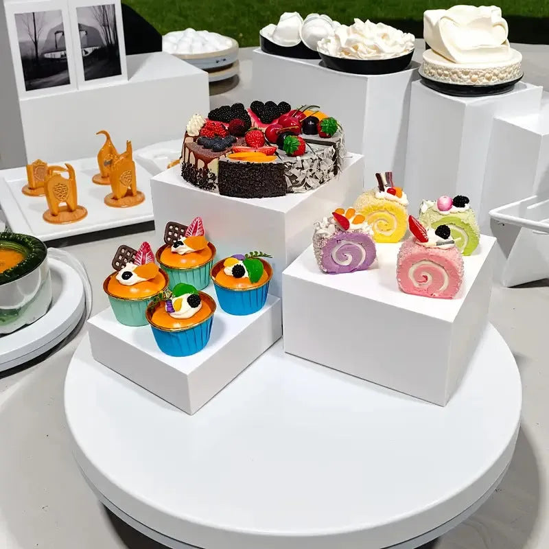 White plastic cube-shaped dessert display stands arranged on countertop for cake presentation