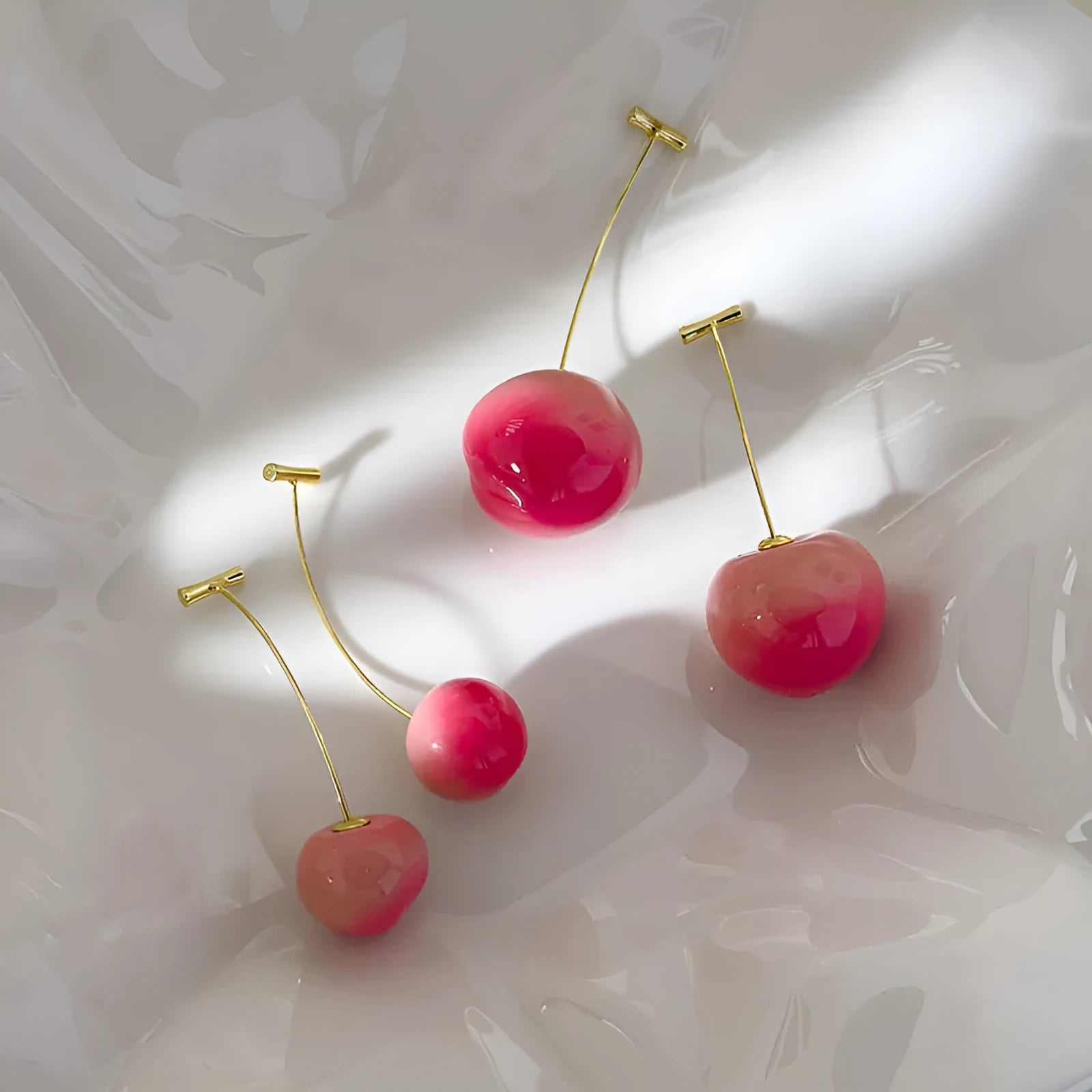 A pair of acrylic peach-shaped dangle earrings with copper hooks, shown in two size variants.