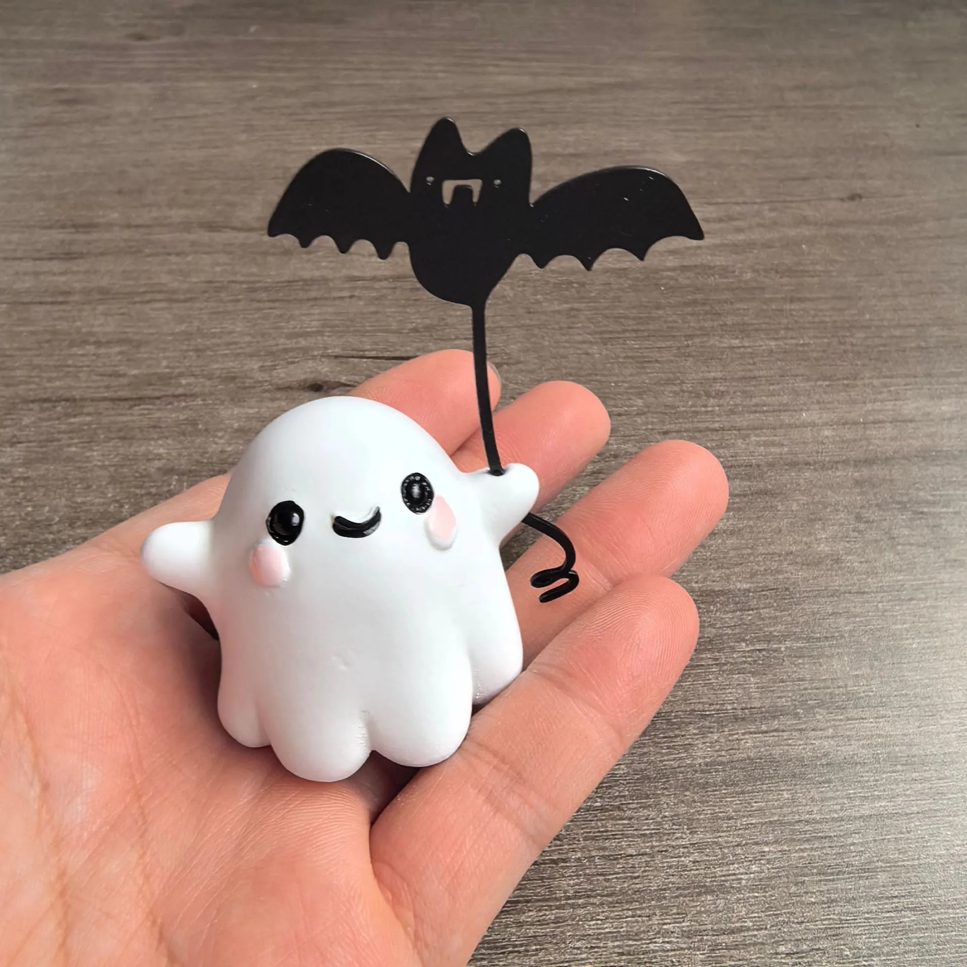 Miniature resin statue of a ghost holding a bat next to a walking dog, a Halloween decoration.