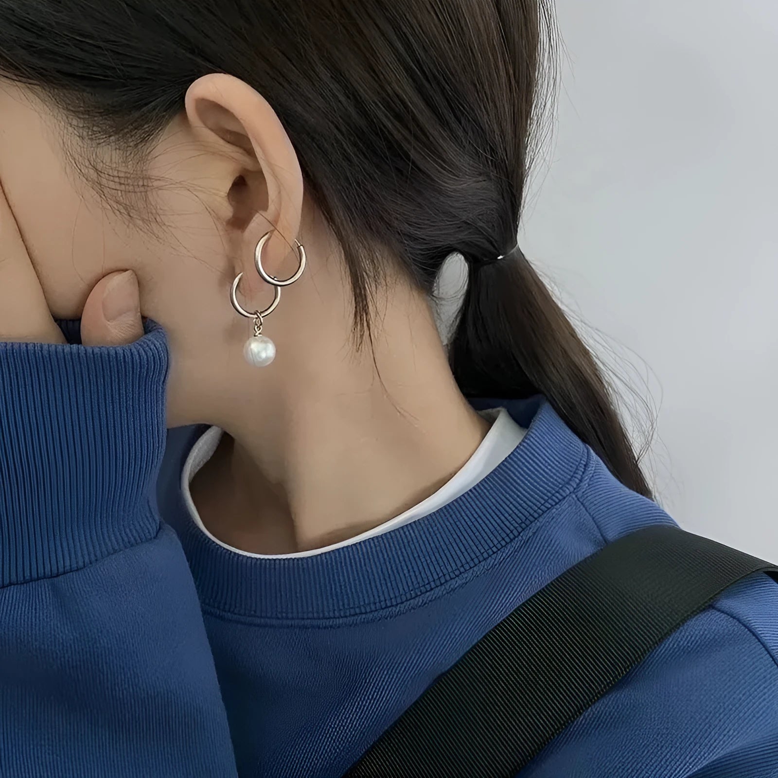 A pair of geometric pearl-coloured alloy earrings with titanium steel posts on a white background.