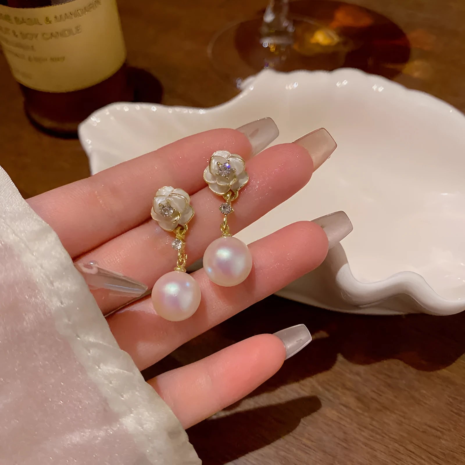 A pair of camellia flower stud earrings for women with a pearl centre, made from alloy.