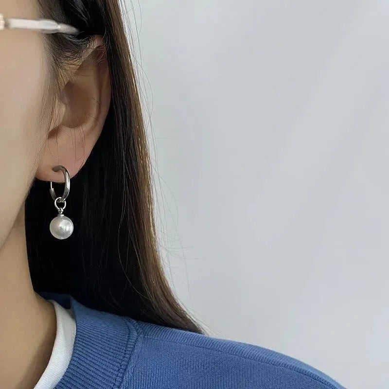 A pair of geometric pearl-coloured alloy earrings with titanium steel posts on a white background.
