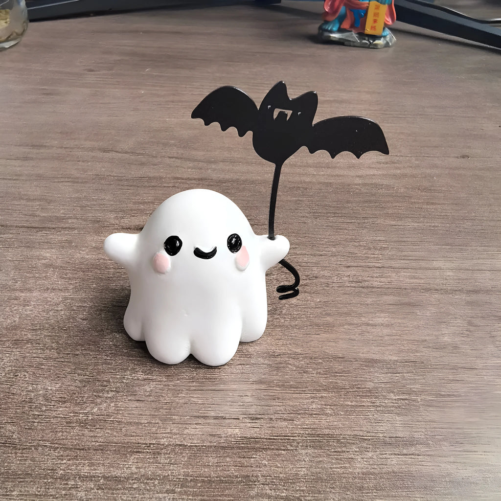 Miniature resin statue of a ghost holding a bat next to a walking dog, a Halloween decoration.