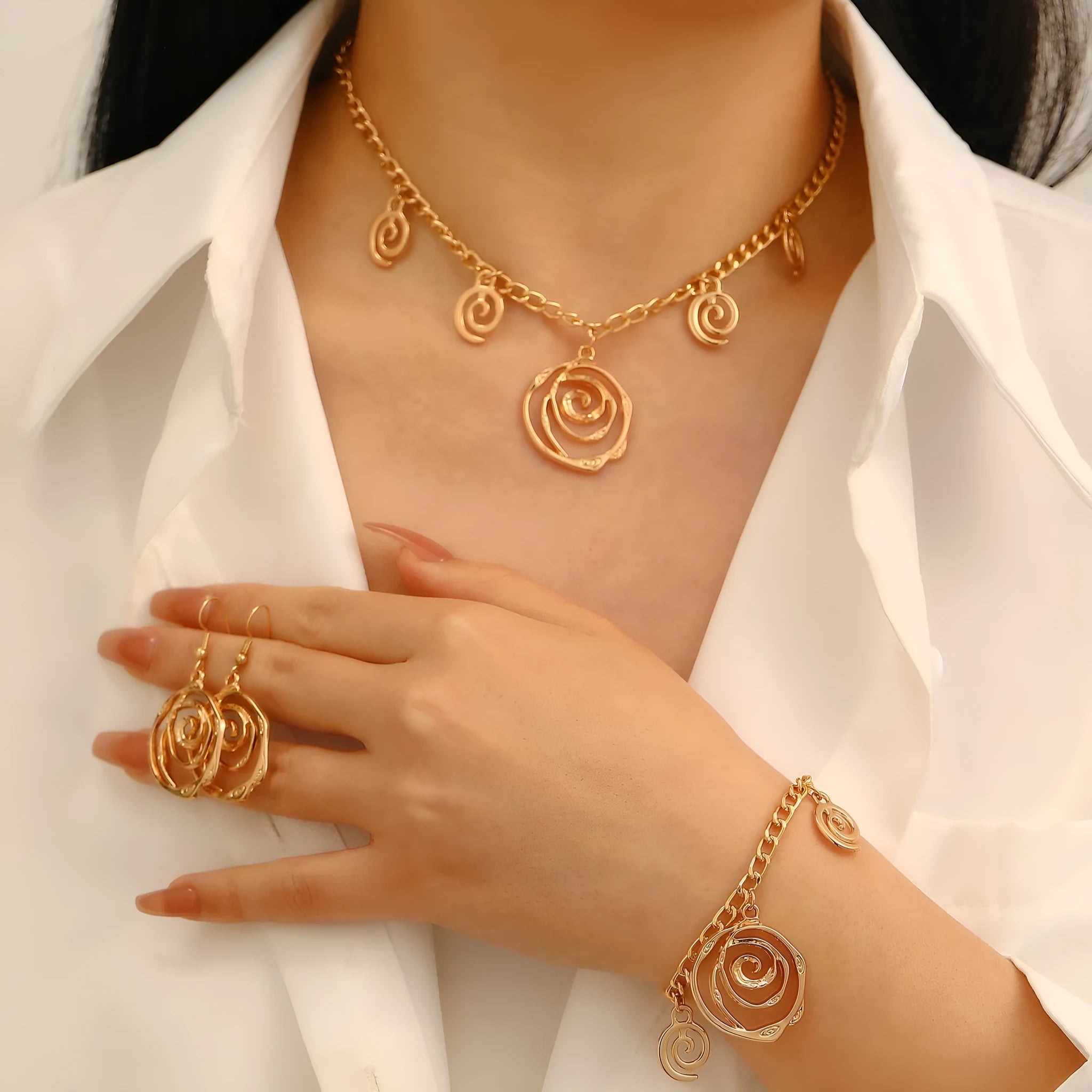 Gold tone spiral donut design necklace, bracelet, and earrings set on a white background.