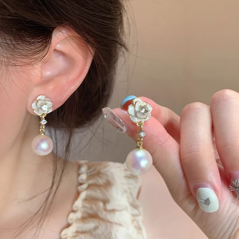 A pair of camellia flower stud earrings for women with a pearl centre, made from alloy.