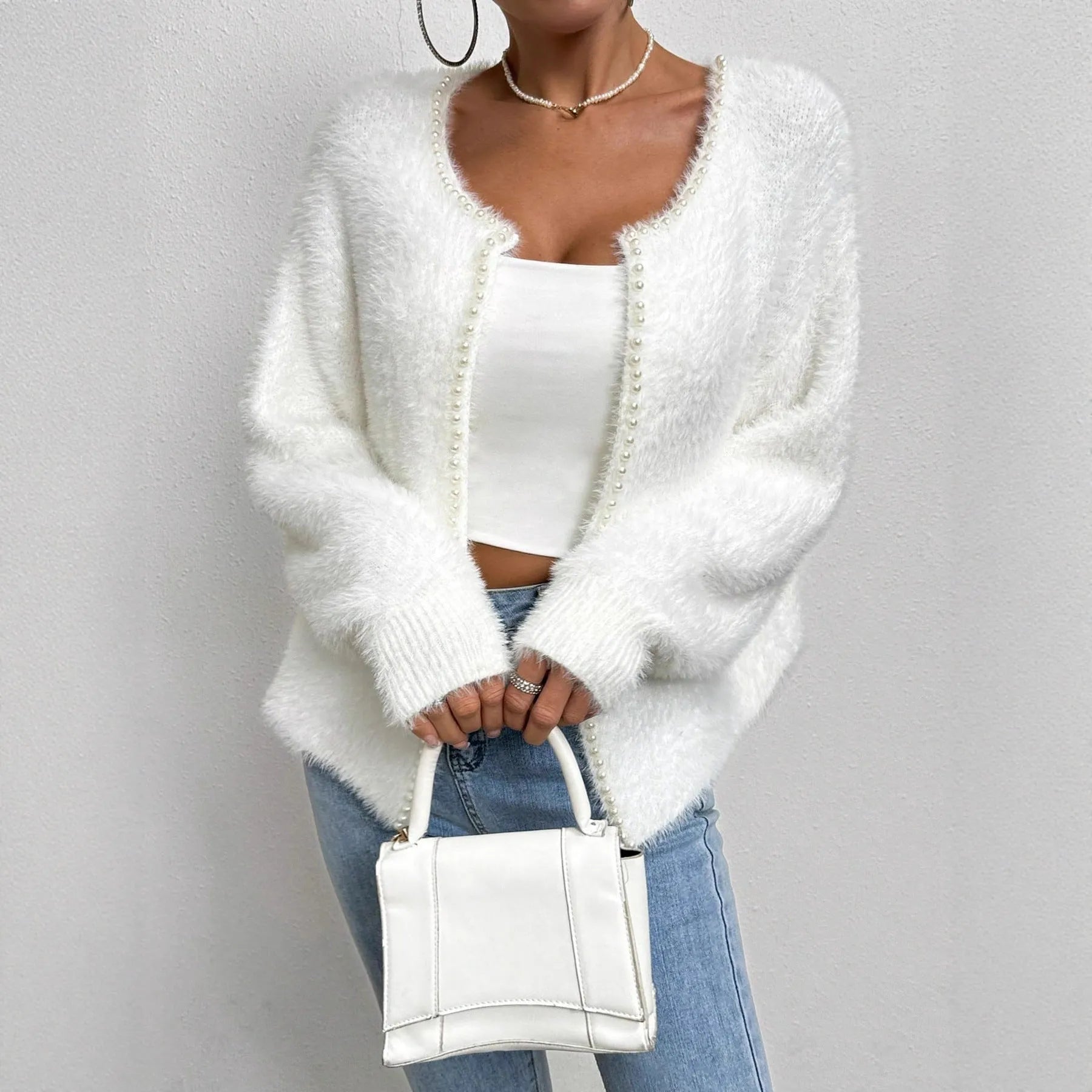 White women's V-neck cardigan with beaded knit detail on a hanger.