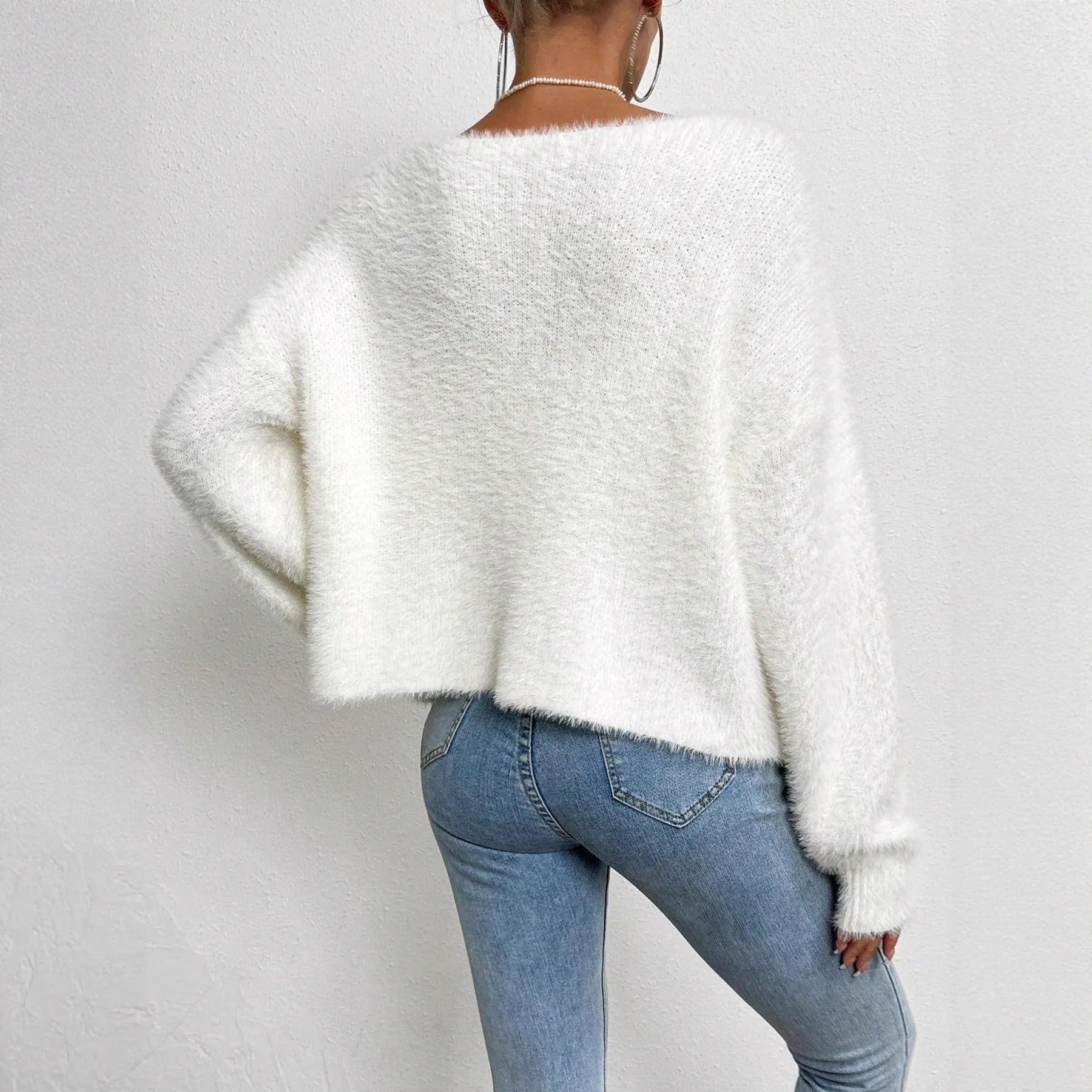 White women's V-neck cardigan with beaded knit detail on a hanger.