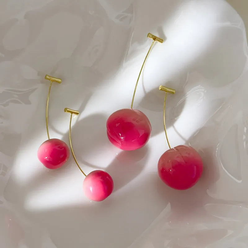 A pair of acrylic peach-shaped dangle earrings with copper hooks, shown in two size variants.