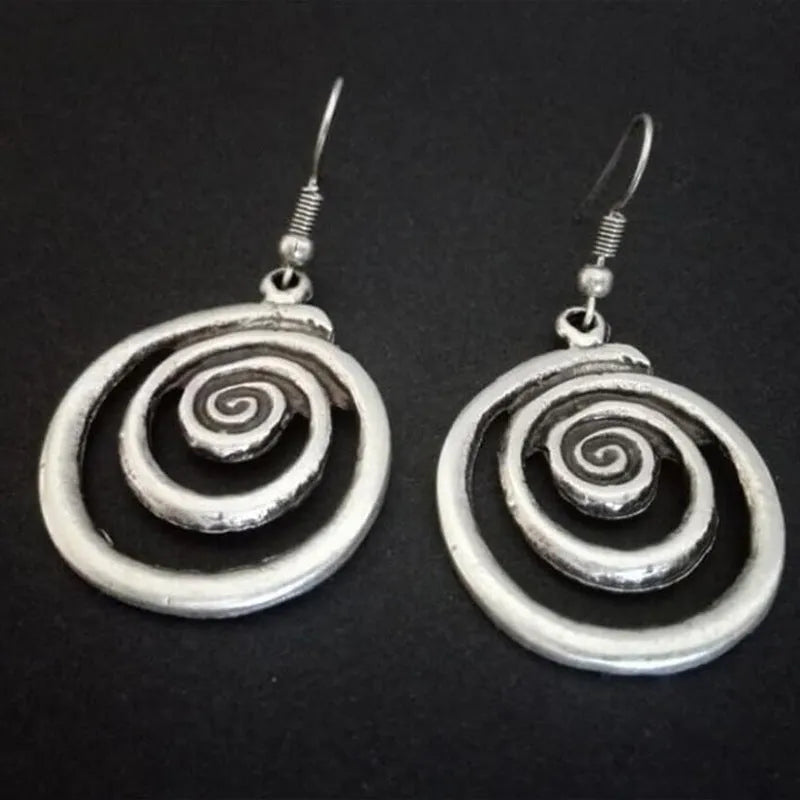 Geometric spiral alloy earrings with distressed silver finish and folk art style.