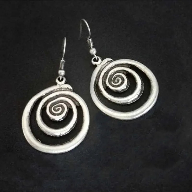 Geometric spiral alloy earrings with distressed silver finish and folk art style.