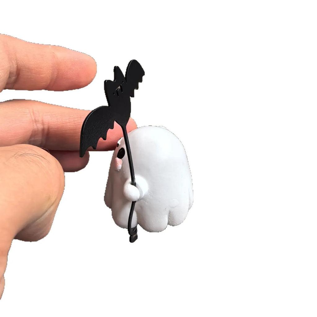Miniature resin statue of a ghost holding a bat next to a walking dog, a Halloween decoration.