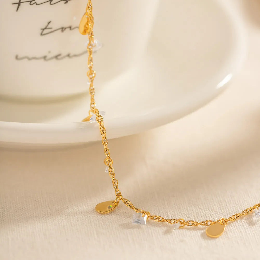 Stainless steel women's anklet with a water drop tassel charm and geometric details.