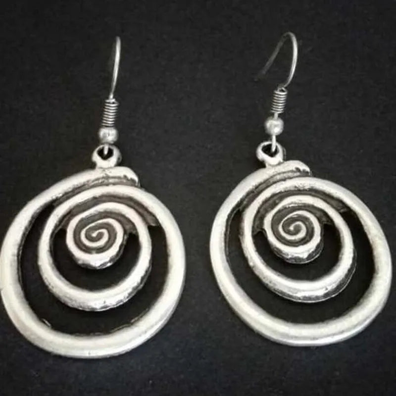 Geometric spiral alloy earrings with distressed silver finish and folk art style.