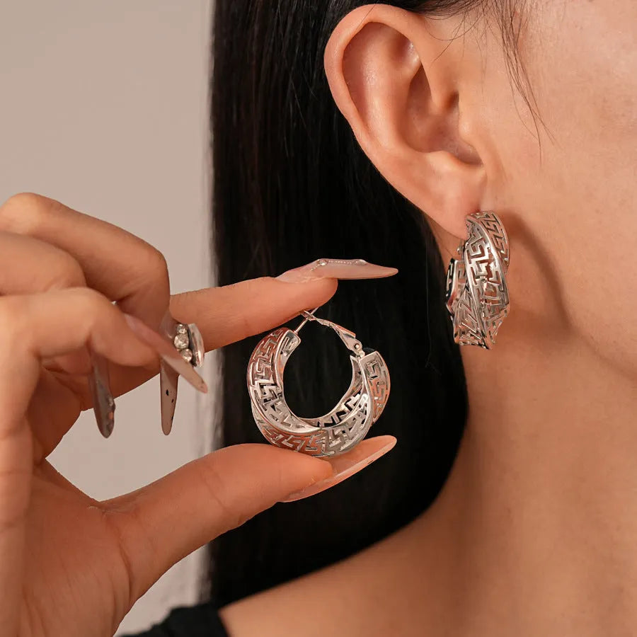 A pair of silver geometric women's stud earrings with a twisted round hollow design.
