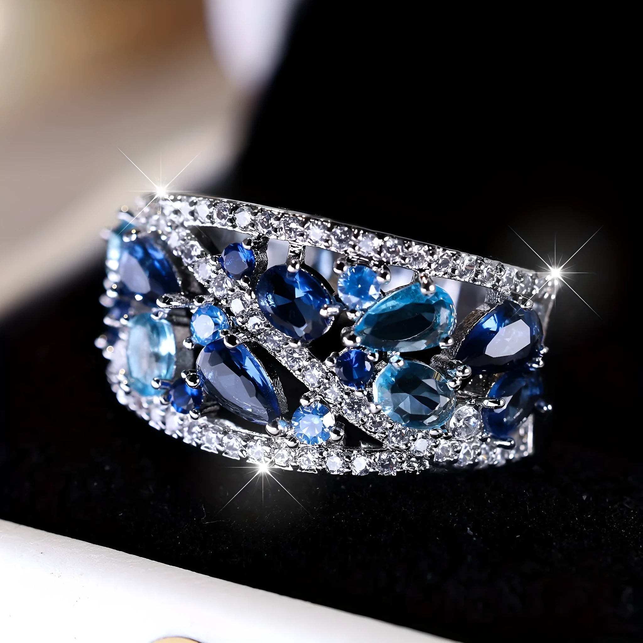Women's hollow round fashion ring in gold tone with blue stones, showing openwork design.