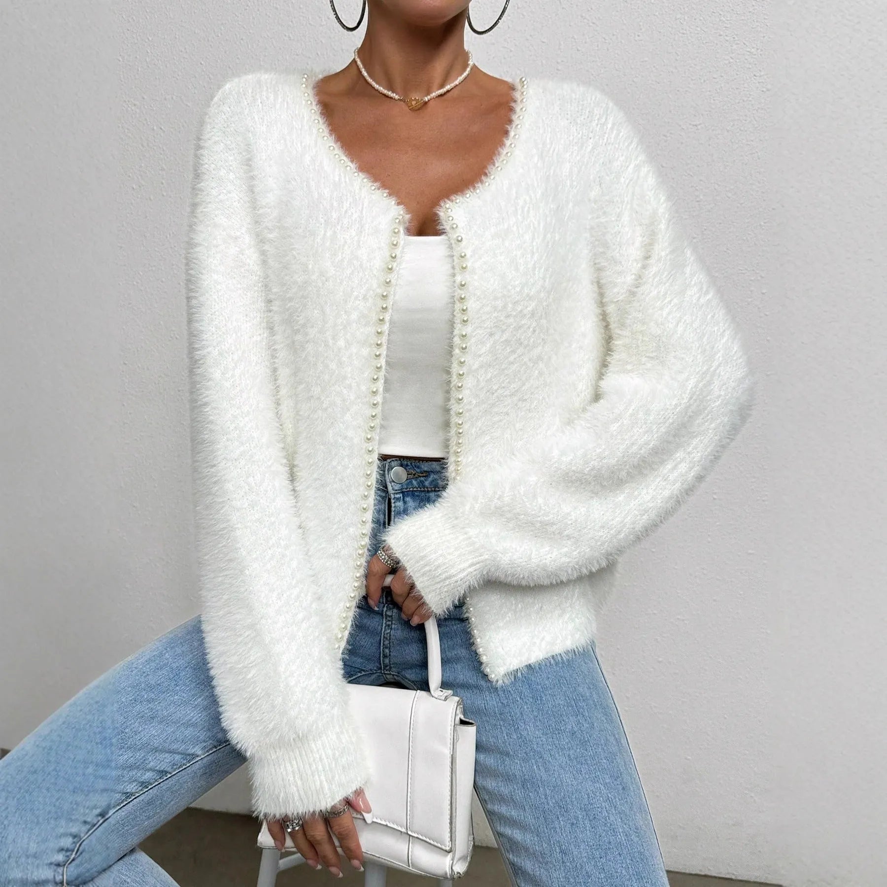 White women's V-neck cardigan with beaded knit detail on a hanger.