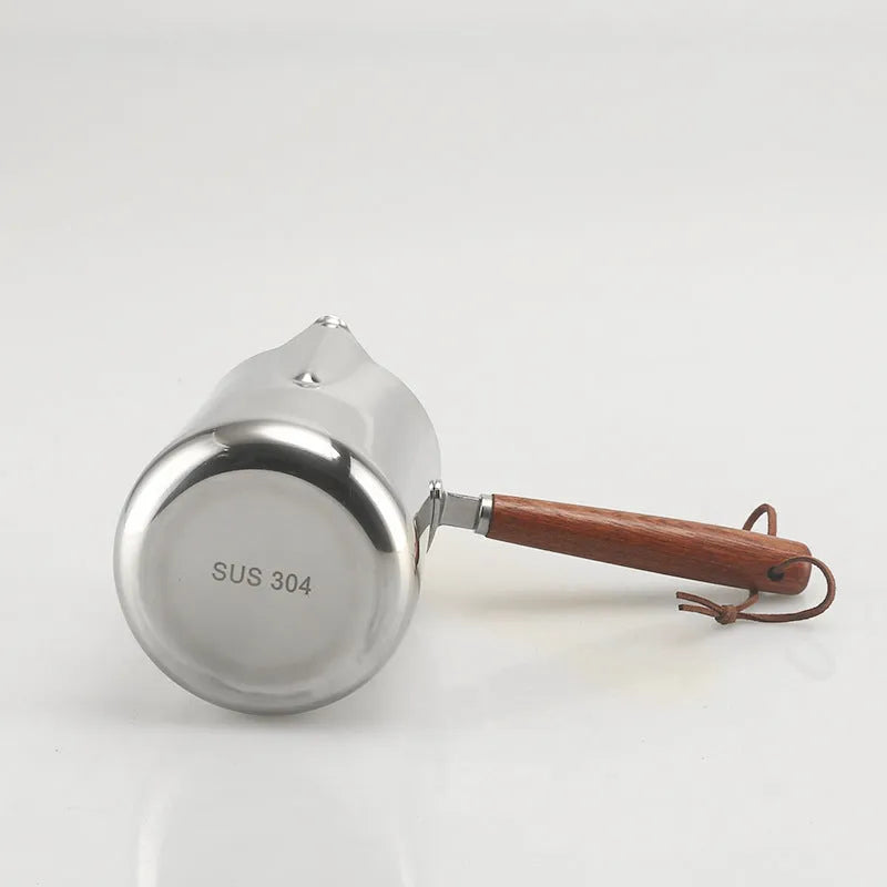 Stainless steel coffee cup with wooden handle showing interior measurement scale for latte art