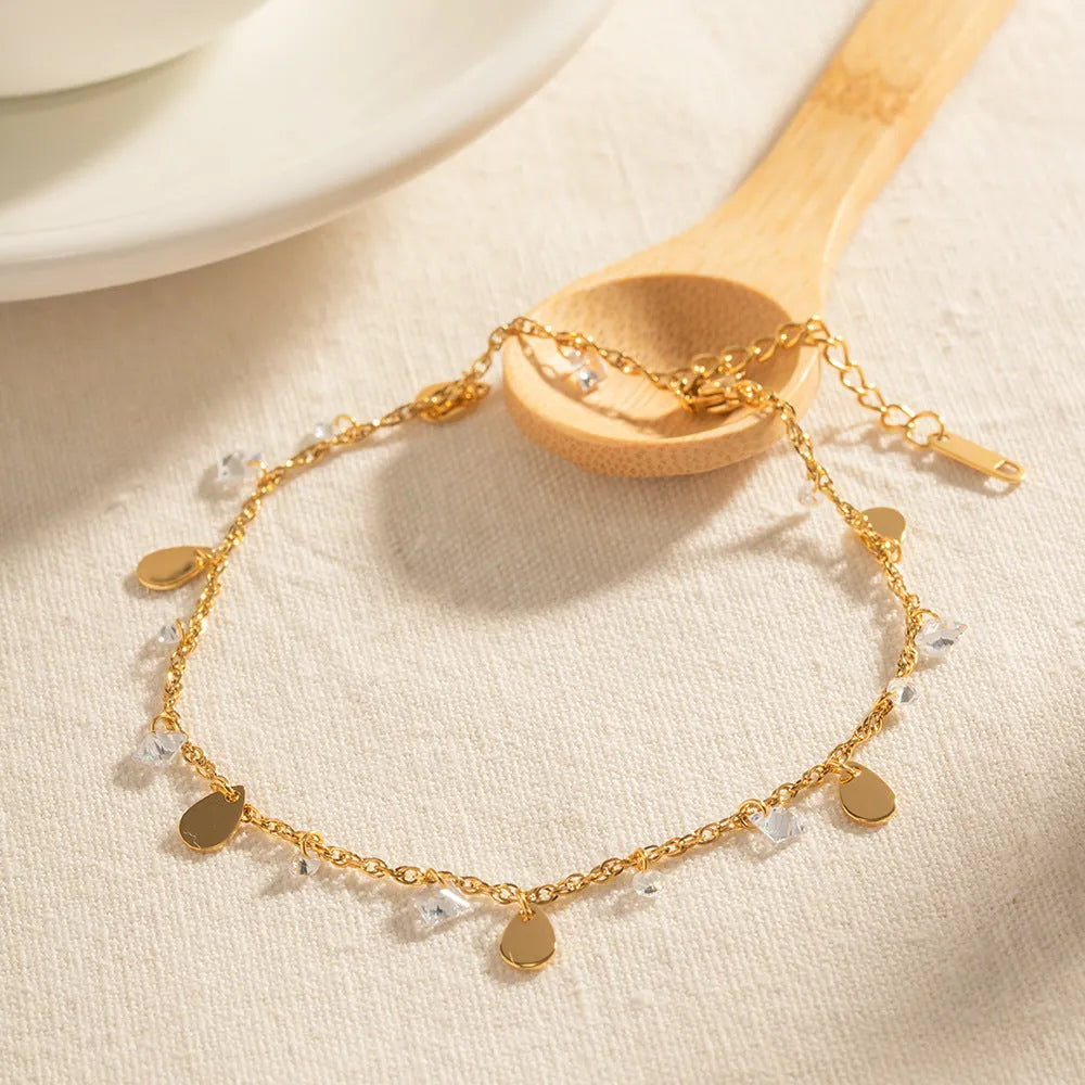 Stainless steel women's anklet with a water drop tassel charm and geometric details.