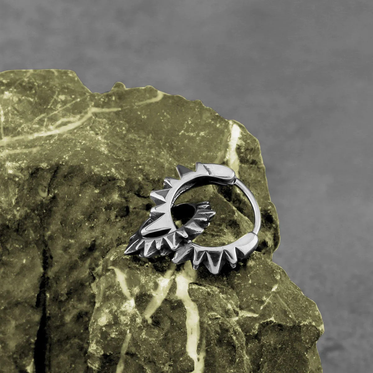A pair of polished steel-coloured stainless steel round ring earrings on a simple background.